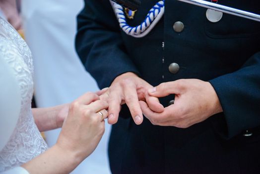 the bride and groom during the wedding ceremony put wedding rings on their fingers.