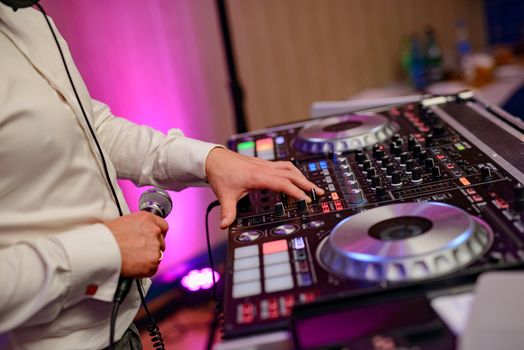 DJ plays music at wedding party. Colorful light rays.