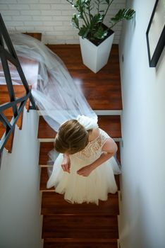 Bridesmaid helping slender bride lacing her wedding white dress, buttoning on delicate lace pattern with fluffy skirt on waist. Morning bridal preparation details newlyweds. Wedding day moments, wear.