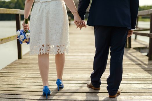 Bride and groom at a photo session in the nature. Lake and pier.