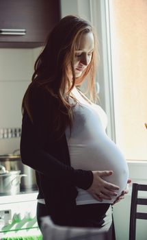 A photograph of pregnant woman relaxing on chair at desk in room.