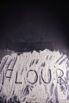 Word food written with flour on black background.
