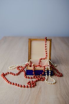 A photograph of gift box and red beads necklace on wooden background