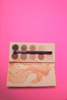 Palette of colorful eye shadows. Pink background.