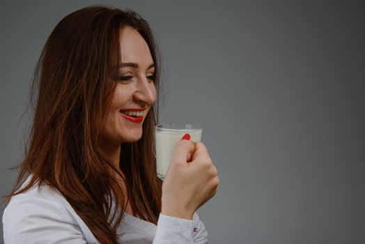 Cheerful girl holding milk mug in hand. Milk is a source of calcium