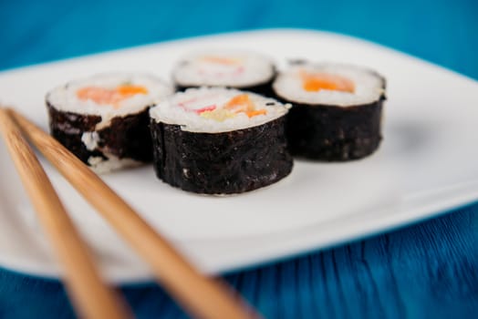 Appetizing tasty Japan rolls on a plate isolated on blue wooden background