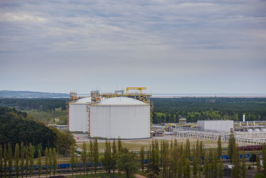 Large industrial tanks for petrochemical plant, oil and gas fuel or water in refinery or power plant for industrial plant on blue sky background.