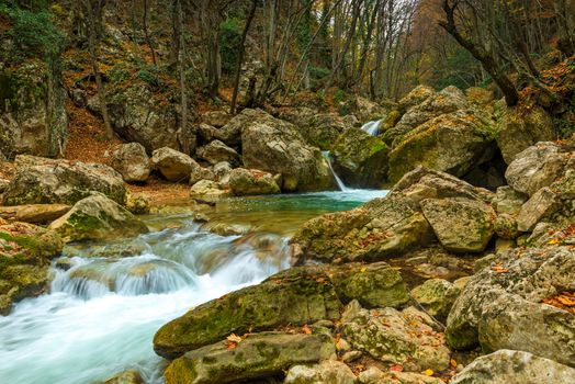 Autumn landscape - large boulders in the gorge of the mountains, where the fast cold river flows