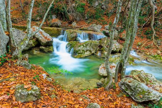 a postcard view in a beautiful natural location in the autumn mountain forest small waterfalls and a river
