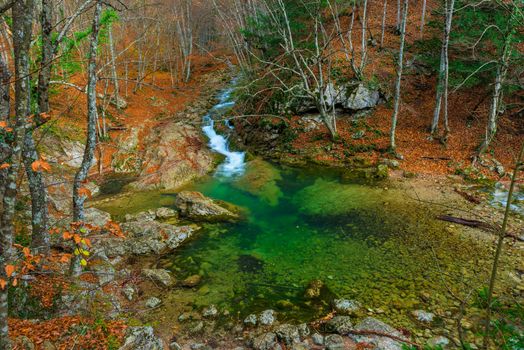 Blue lake and mountain stream flowing in a canyon in the mountains in the autumn afternoon, beautiful view