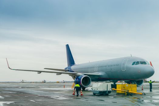 The plane in the parking lot at the airport, airport workers in the frame