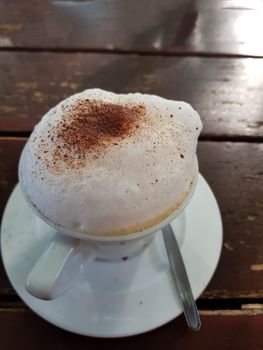 Closeup on a plain white coffee cup with milk foam after latte style on brown wooden table top in a cafe.
