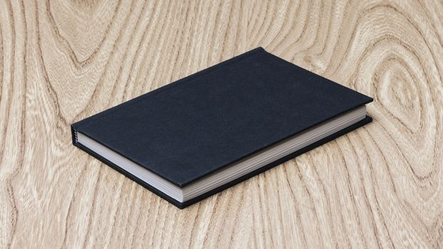 Black book on wooden table, close up