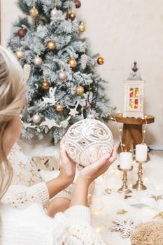 A woman holds a pretty glittering ornate Christmas bauble for the tree