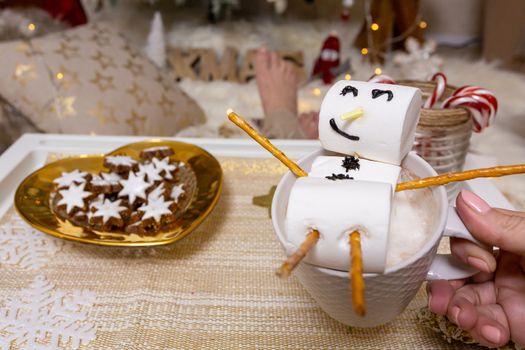Marshmallow snowman floats on top of the mug of hot chocolate at Christmas time