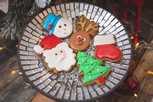 Iced gingerbread cookies by the festive Christmas tree in various shapes like, santa claus, snowman, reindeer, etc.  Not all cookies in focus