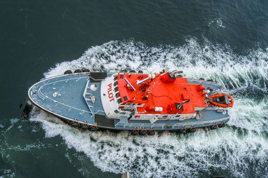 An Orange and White Pilot Boat From Above Cutting Through Water.