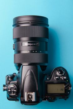 Professional modern DSLR camera against blue background