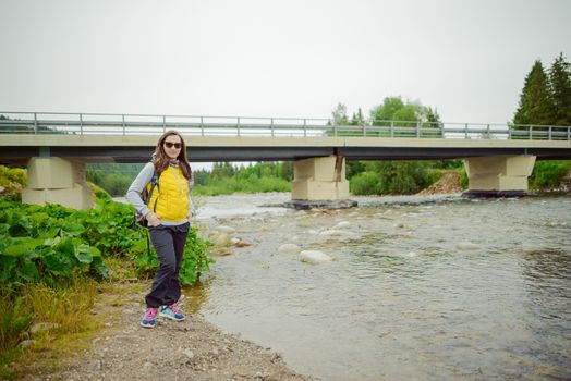 Female tourist standing beside the mountain river.