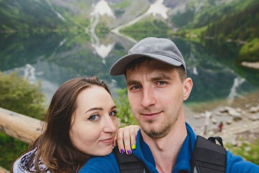 Happpy couple taking selfie withe lake background in the mountains