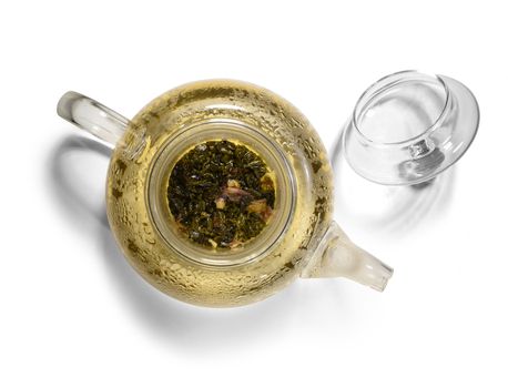 Hot green tea in glass teapot on white background.