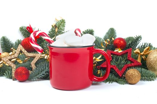 Cocoa in red mug with marshmallows and candy cane and fir tree branches and red and golden baubles and stars isolated on white background