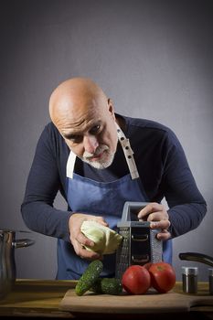 Gray-haired man in the kitchen preparing a salad