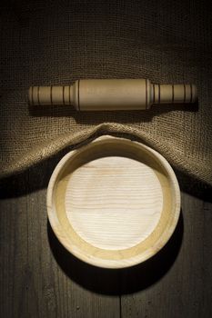 Wooden plate and rolling pin on an old burlap covered table