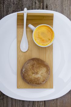 Bun and cup of coffee on a wooden tray