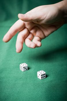 Hand throws dice on a table with green cloth