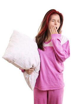 Portrait of tired young girl in pajamas holding a white pillow and yawning, with closed eyes and covering her open mouth with her palm, isolated on white background. Health balance sleep deprivation concept.