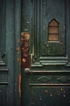 Vintage weathered green wooden door with metal doorknob. Old wooden door in Budapest.