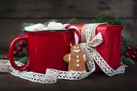 Cocoa in red mug with marshmallows and candy cane and Christmas fir tree on dark wooden background