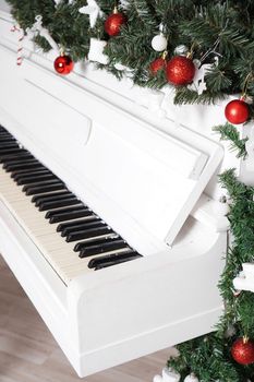 Keys on white upright piano with christmas decor with red balls