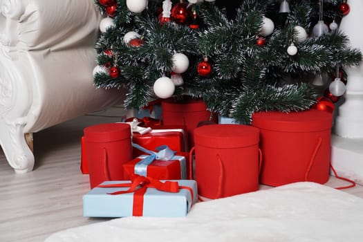 Lots of beautifull wrapped Christmas presents in round boxes in red and blue under the Christmas tree. Concept of Christmas and New Year holidays.