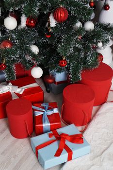 Lots of beautifull wrapped Christmas presents in round boxes in red and blue under the Christmas tree. Concept of Christmas and New Year holidays.