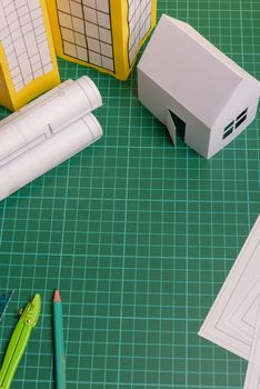 White family paper house over block of flats on yellow background paper. Minimalistic and simple concept, style. Copy space. Vertical orientation.