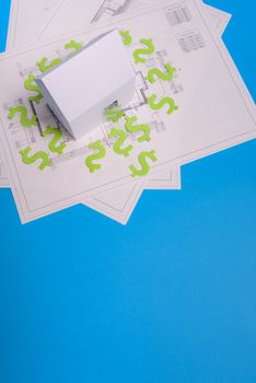 Paper skyscrapers , us dollar money, house projects plan and blueprints on blue background paper. Minimalistic and simple concept, style. Horizontal orientation. View from above. Copy space.