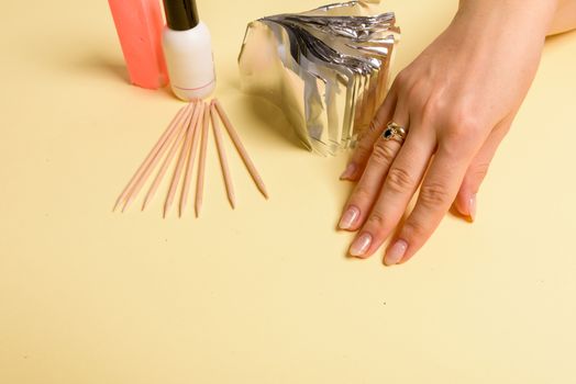 The procedure for removing varnish from nails hybrid nails in progress. Gel nail polish remover foils on woman's hands