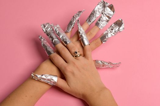 The procedure for removing varnish from nails hybrid nails in progress. Gel nail polish remover foils on woman's hands