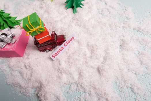 a toy car carries presents under the Christmas tree at snow. view from above. copy space