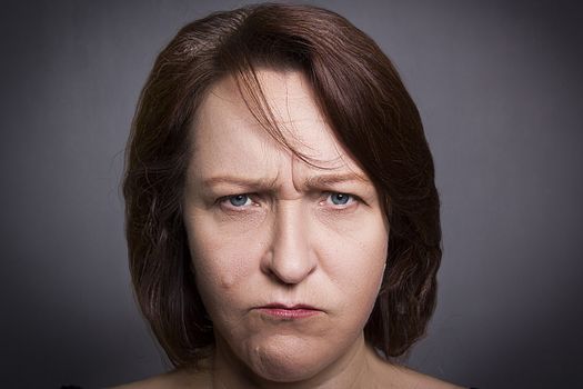Woman grimaces in front of camera on black background