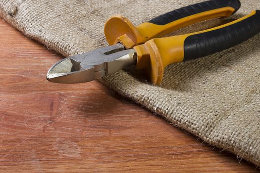 Wire cutters on wooden table laid by sacking