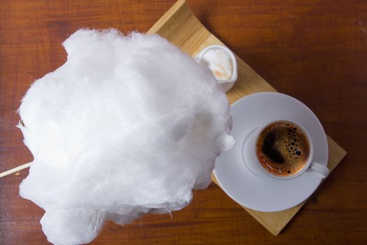 Cotton candy and cup of coffee on a wooden table