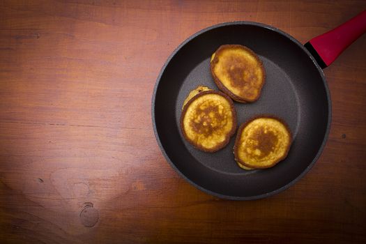 Fritters in a pan on a wooden table