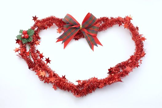 Christmas red festive tinsel for decorationin the shape of heart on red background , TEXT in space