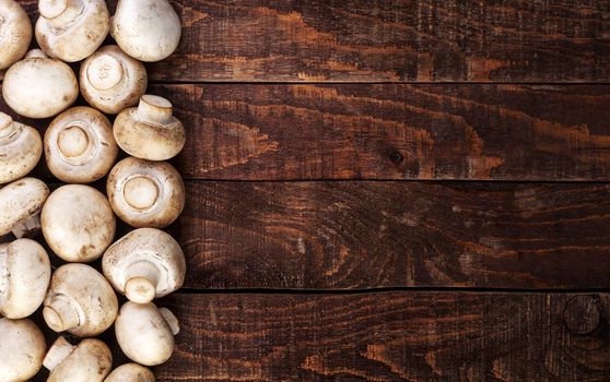 Heap of fresh champignon mushrooms on wooden table, top view. Copy space