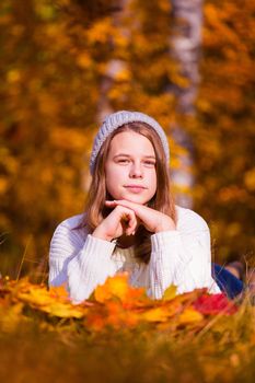 Portrait of pretty nice teenage girl laying in autumn park , background with copy space for text