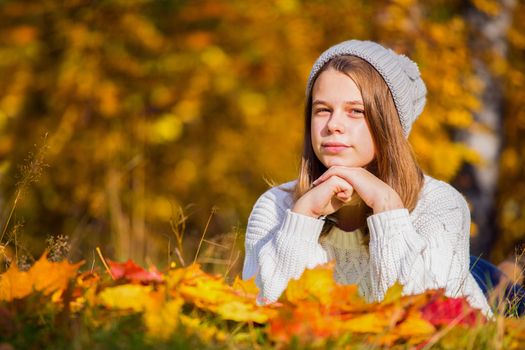 Portrait of pretty nice teenage girl laying in autumn park , background with copy space for text