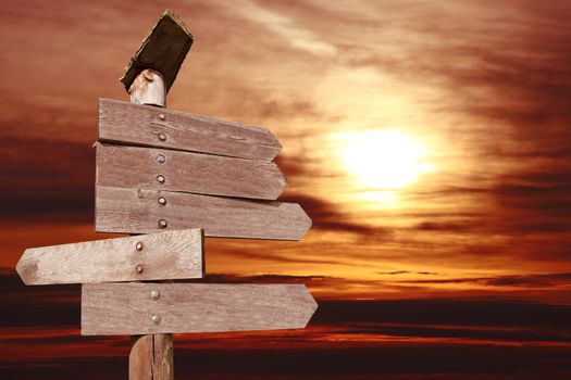 directional wooden arrows on sunset background